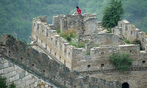 A man rests on a guard tower on the Great Wall of China.