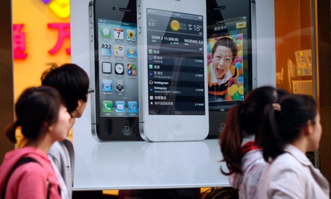Chinese walk in front of an iPhone poster at a phone shop in Beijing Saturday, April 7, 2012. Chinese walk in front of an iPhone poster at a phone shop in Beijing Saturday, April 7, 2012.