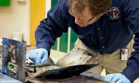 National Transportation Safety Board engineer Matt Fox examines parts from the battery involved in the  787 fire in Boston.