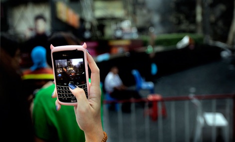 A girl takes a photograph from her mobile phone in downtown Bangkok. A girl takes a photograph from her mobile phone in downtown Bangkok.