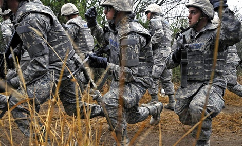 Air Force basic trainees in body armor use hand signals as they take a knee during a tactical drill movement. Air Force basic trainees in body armor use hand signals as they take a knee during a tactical drill movement.
