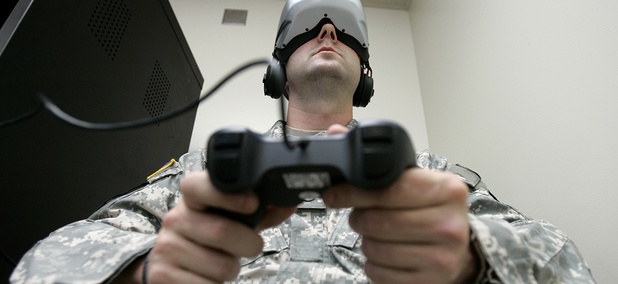 U.S. Army Staff Sgt. Jeff Ebert wears a virtual-reality headset and holds a video-game controller as he demonstrates an experimental virtual-reality computer simulation. U.S. Army Staff Sgt. Jeff Ebert wears a virtual-reality headset and holds a video-game controller as he demonstrates an experimental virtual-reality computer simulation.