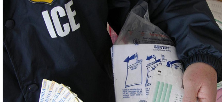  An ICE officer holds fake test scores and ID cards after a bust on a fake student visa ring in 2010.