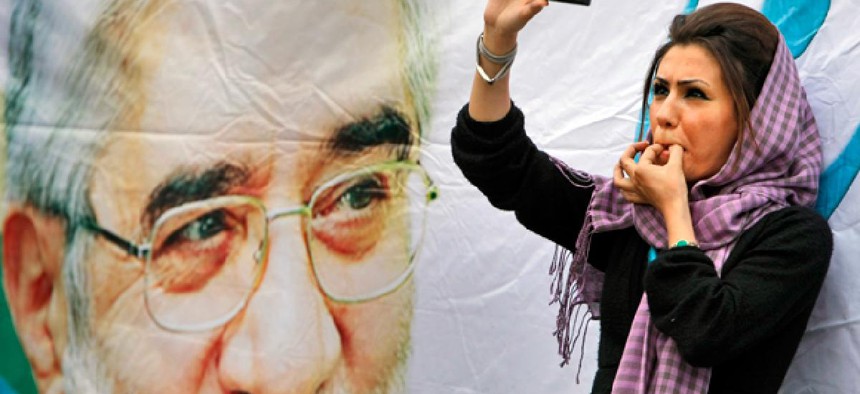 An Iranian protester films an election rally in Tehran on her smart phone. 