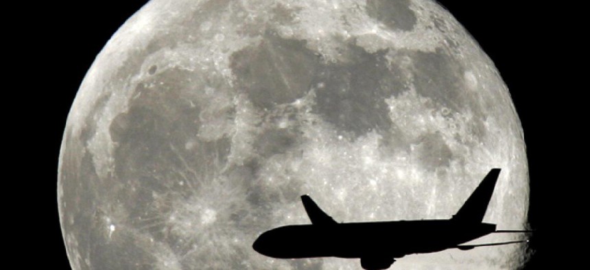 A jet plane passes in front of the full moon. 
