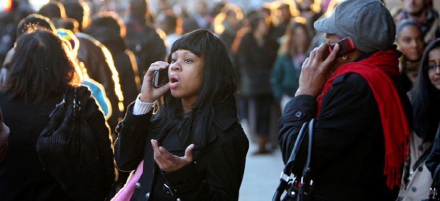 Commuters talk on their phones while waiting in a line to board buses into Manhattan in the wake of Hurricane Sandy.