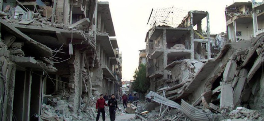 Syrian citizens walk in a destroyed street that was attacked on Wednesday by Syrian forces warplanes.