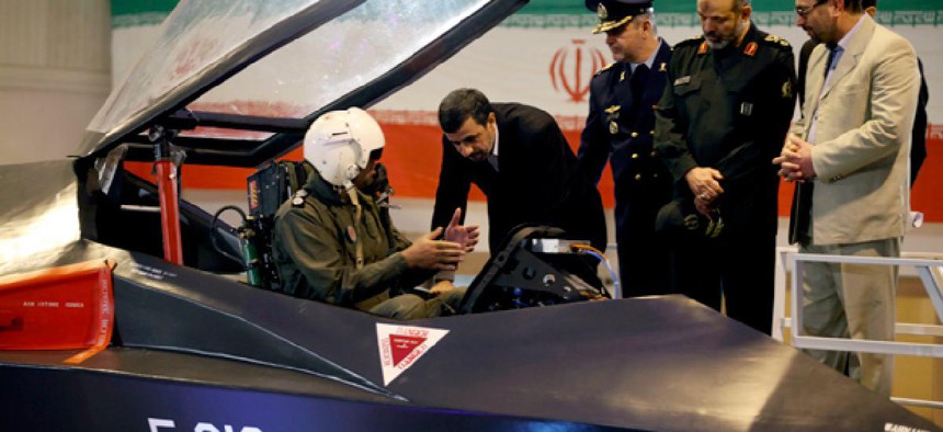 Iranian President Mahmoud Ahmadinejad, center, listens to an unidentified pilot during a ceremony to unveil Iran's newest fighter jet, Qaher-313.