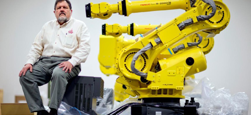 Rosser Pryor, Co-owner and President of Factory Automation Systems, sits next to a new high-performance industrial robot at the company's Atlanta facility.