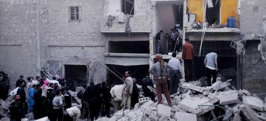 In this Monday, March 18, 2013, citizen journalism image Syrian citizens stand on rubble of houses that were destroyed due to Syrian forces airstrikes.