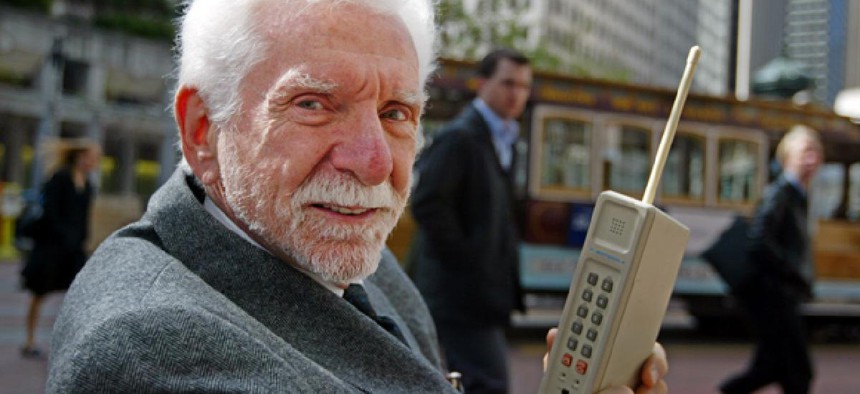 Martin Cooper, chairman and CEO of ArrayComm, holds a Motorola DynaTAC, a 1973 prototype of the first handheld cellular telephone.