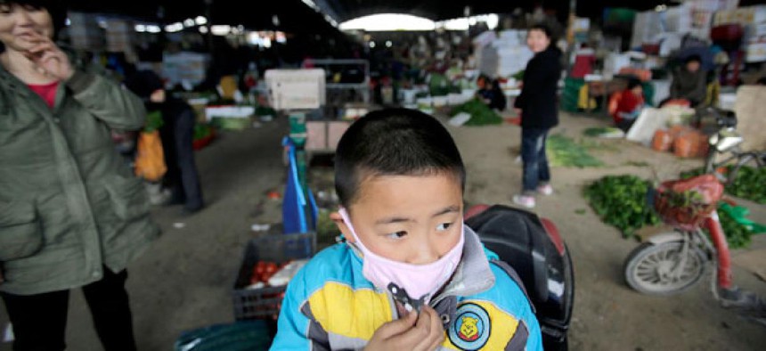 A child wears a mask near the closed poultry section at the Huhuai agricultural market where the H7N9 bird flu was detected by authority in Shanghai, China.