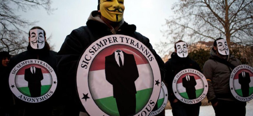 Protestors wearing Guy Fawks masks hold the logos of the international hacker group Anonymous during a demonstration against online censorship laws.