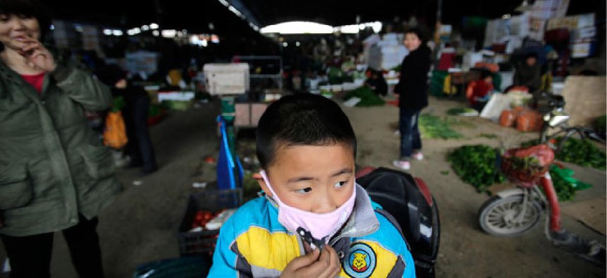 A child wears a mask near the closed poultry section at the Huhuai agricultural market where the H7N9 bird flu was detected by authorities in Shanghai, China.