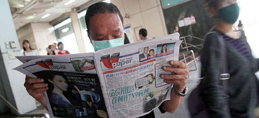 A Taiwanese man wearing a mask reads newspaper titled "Taiwan has confirmed its first case of H7N9" at a subway station in Taipei, Taiwan.