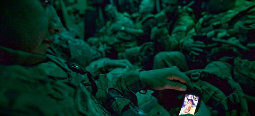 Staff Sgt. Rulberto Qjendismiranda with the U.S. Army's 2nd Battalion 27th Infantry Regiment looks at his mobile phone while aboard a military transport flight.