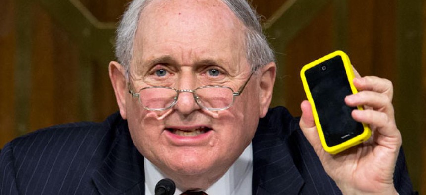 Sen. Carl Levin, D-Mich. holds up his own Apple iPhone while questioning Apple CEO Tim Cook.
