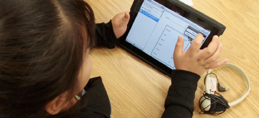 A young girl in a special education classroom reads a worksheet on an iPad in 2011.