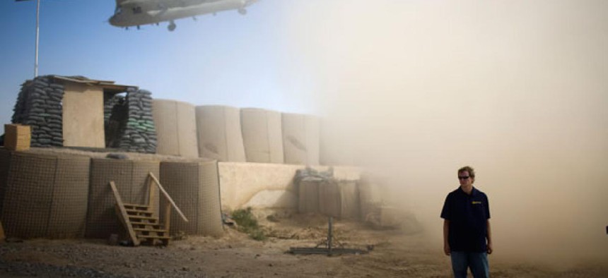 A U.S. contractor stands while a helicopter departs over the gatepost at Combat Outpost Terra Nova in Kandahar, Afghanistan.