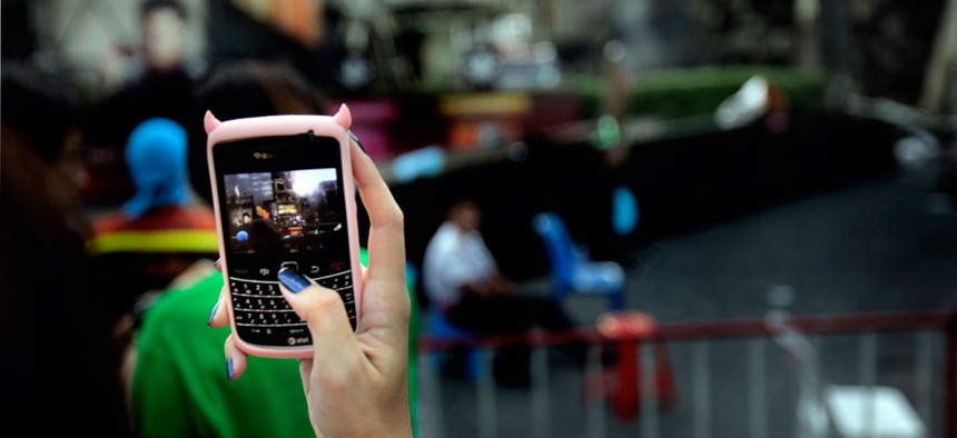 A girl takes a photograph from her mobile phone in downtown Bangkok.