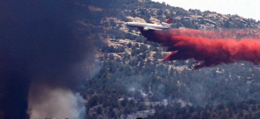 An aerial tanker drops fire retardant on a wildfires threatening homes near Yarnell, Ariz., Monday, July 1, 2013. 