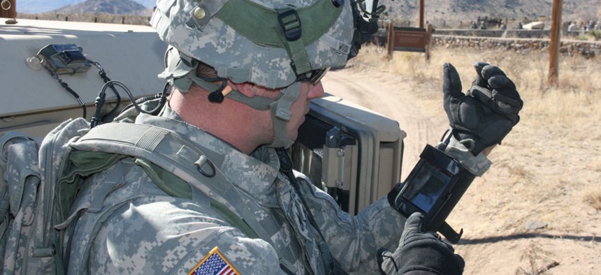 A soldier checks an iPhone during a field exercise.