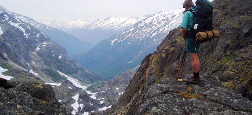 A hiker stands on rock near False Summit looking south at Klondike Gold Rush National Historical Park in Alaska.
