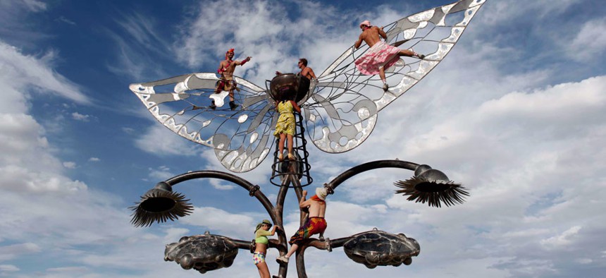 Burning Man participants reach for the skies in a different way, by climbing on an art structure during the festival.