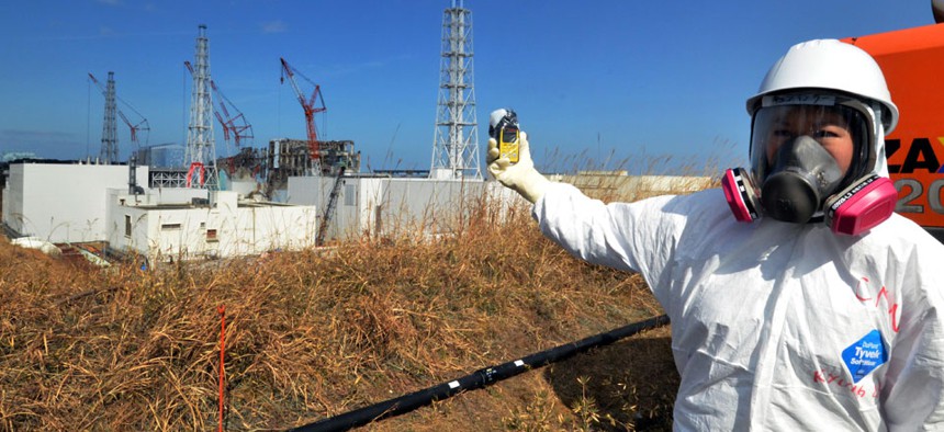A journalist checks radiation level with her dosimeter near stricken Fukushima Dai-ichi nuclear power plant of Tokyo Electric Power Co.