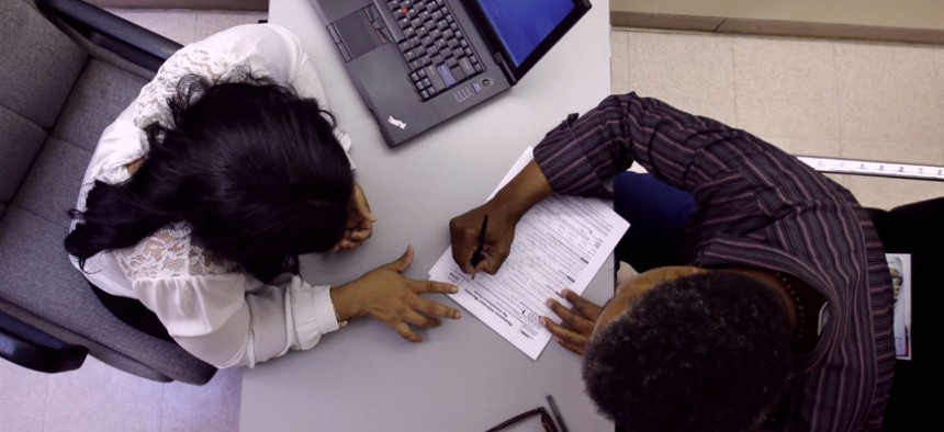 Clinical applications counselor Rachael Richardson, left, works with Louis Peters at the Henry J. Austin Health Center, in Trenton, N.J., as he and others fill out papers to sign up for new plans through the health insurance exchange.