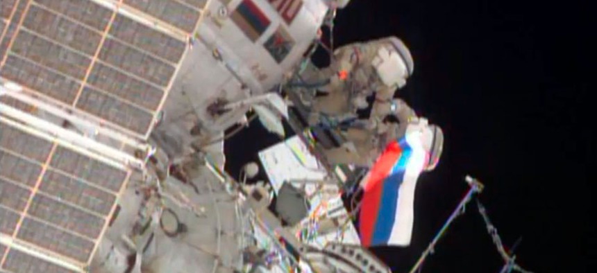 Cosmonauts wave a Russian flag near the end of their spacewalk outside the International Space Station.