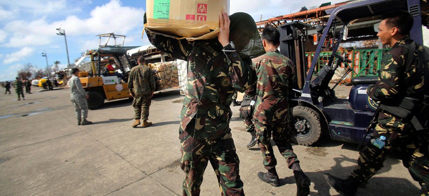 A Philippine soldier carries relief goods delivered in the airport in Tacloban city.