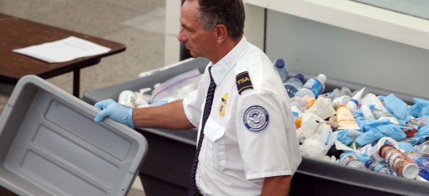 A  TSA worker empties bottles into a bin filled with confiscated items at Denver International Airport. 