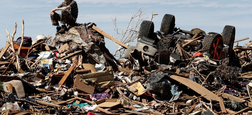 A man sits atop a pile of rubble after a tornado came through Oklahoma in May. 