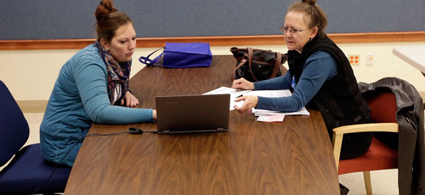 Amanda Deardorff, left, a health enrollment navigator with Open Door Health Solutions, helps Valerie Kazer through the process of signing up for coverage under the Affordable Care Act in Muncie, Ind.