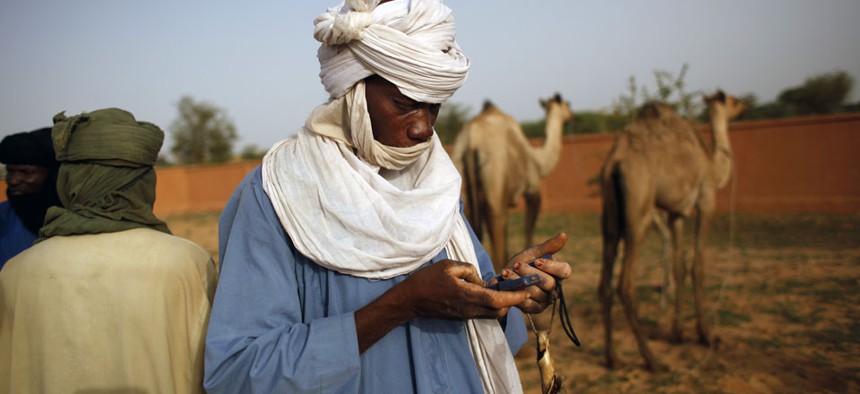 A buyer used two cells phones as he is ready to conclude a deal on a camel at the livestock market in the desert village of Sakabal, Niger.