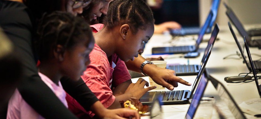 Black Girls Code (BGC) workshop volunteers guide two students during an app building session at Google.