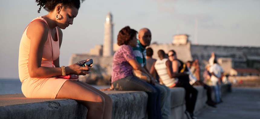 A woman uses her cellphone as she sits on the Malecon in Havana, Cuba