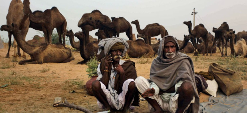 An Indian camel herder, left, speaks on his phone at the annual cattle fair in Pushkar, India.