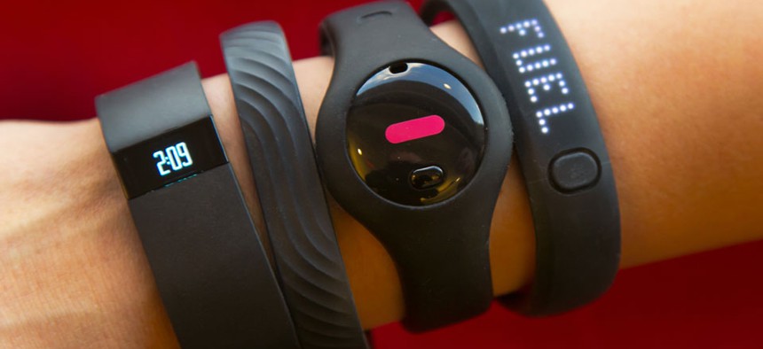 Four fitness trackers are worn, including the Fitbit Force and Nike FuelBand SE.