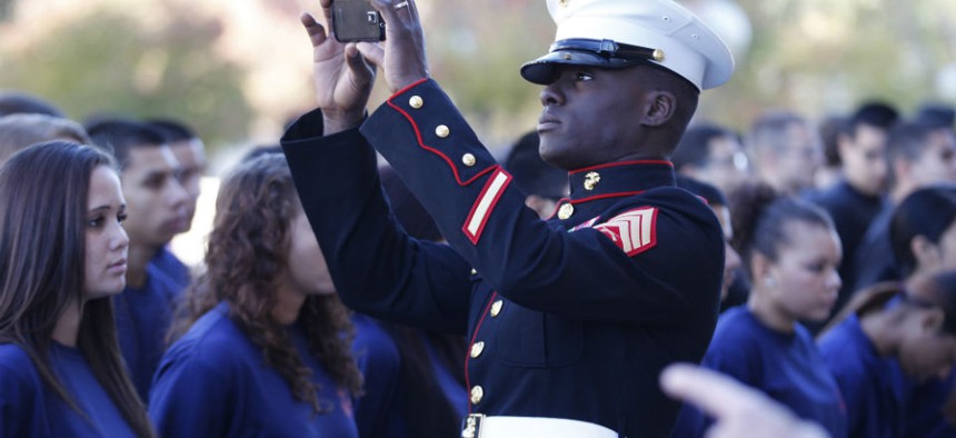 A Marine takes a smartphone photo of military enlistees as they line up before taking their oath in front of Dallas City Hall 