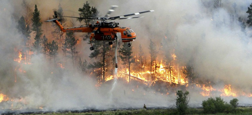 A helicopter drops water as it assists in firefighting efforts at the Taylor Creek fire 25 miles southeast of Ashland, Montana.
