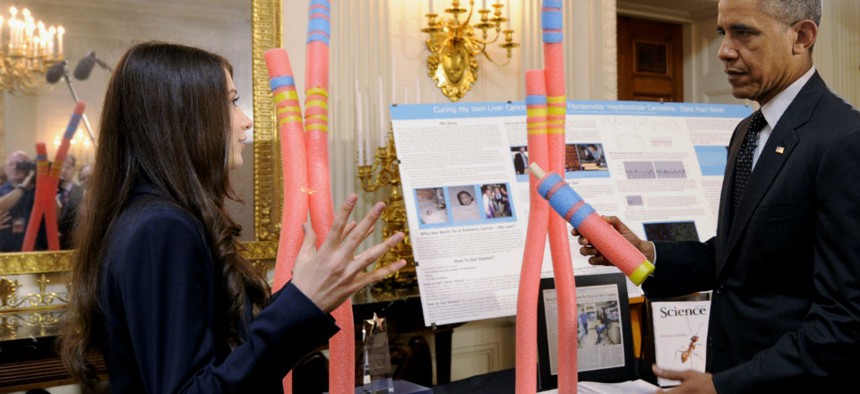 President Barack Obama talks with Elana Simon, 18, of New York City, about her cancer research project that is part of the 2014 White House Science Fair exhibit.