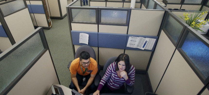 MNsure insurance exchange representatives Carlos Villanueva, left, and Emily Joyce prepare for the Oct. 1 open enrollment debut at the center in St. Paul, Minn. 