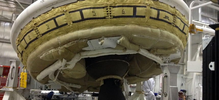 A saucer-shaped test vehicle holding equipment for landing large payloads on Mars in the Missile Assembly Building at the U.S Navy's Pacific Missile Range Facility.