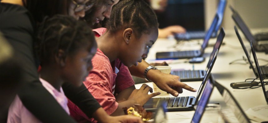 Black Girls Code workshop volunteers work with students during an app building session at Google. 