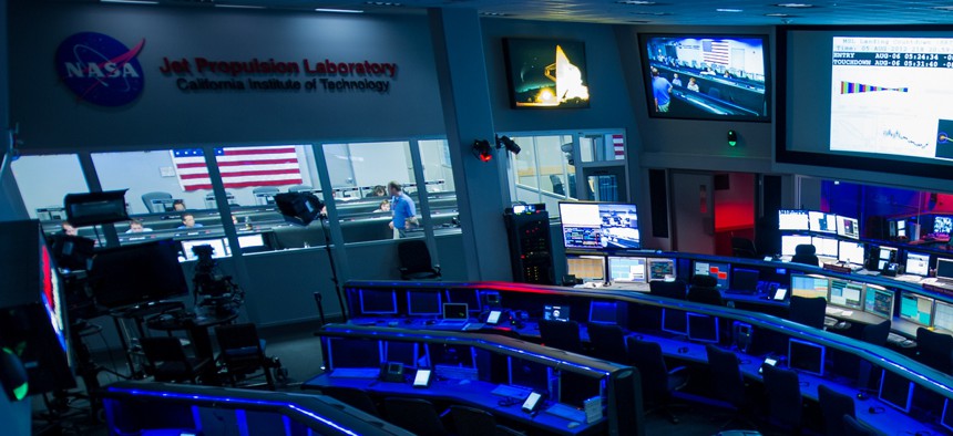 The the control rooms at the Jet Propulsion Laboratory, the Dark Room in the foreground, Deep Space Network control room on the right and the Mars Science Laboratory Mission Support Area back left.