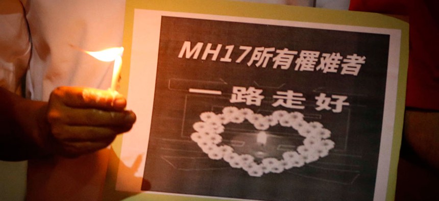 A man holds a sign which reads " MH17 Victims Rest In Peace" during a candlelight vigil for the victims who were on board the Malaysia Airlines jetliner.