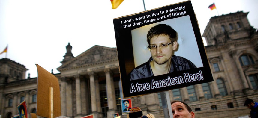Protesters hold posters of former National Security Agency member Edward Snowden in front of the German parliament building.
