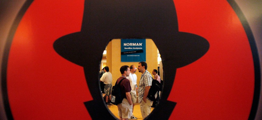 Attendees are seen through a Black Hat logo during the Black Hat and Defcon hacker conferences in Las Vegas. 